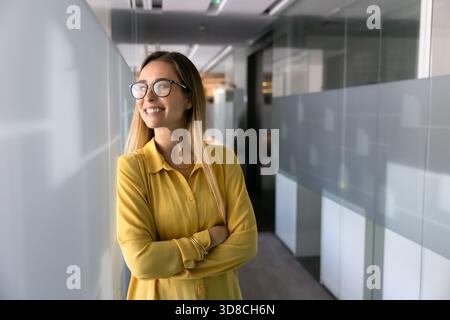 Felice bella giovane donna d'affari in piedi in ufficio Foto Stock