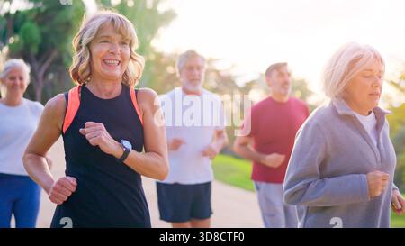 Persone anziane attive felici che fanno jogging insieme in un parco Foto Stock