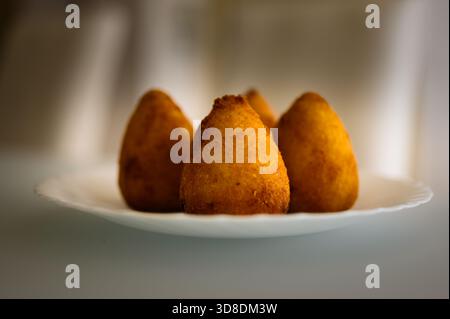 Un primo piano di arancini appena fritti, il classico spuntino siciliano a base di palline di risotto condite ripiene di mozzarella e ragù di carne, ricoperte in un Foto Stock