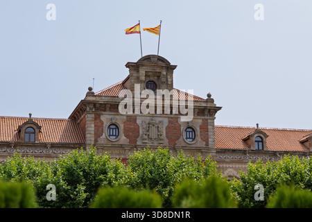 Parlamento della catalogna a barcellona, spagna, che rappresenta l'autogoverno regionale con le sue bandiere che sventolano sotto un cielo limpido Foto Stock