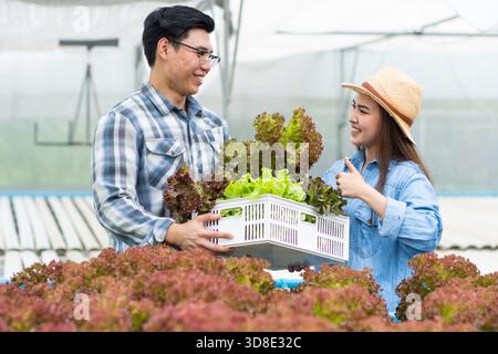 Donna asiatica e uomo contadino che lavorano insieme in un'azienda agricola biologica di verdure con insalata idroponica Foto Stock