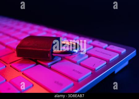 Un lucchetto poggia sulla tastiera di un computer, simboleggiando la sicurezza informatica e la protezione dei dati. La scena evidenzia l'importanza di salvaguardare le informazioni Foto Stock