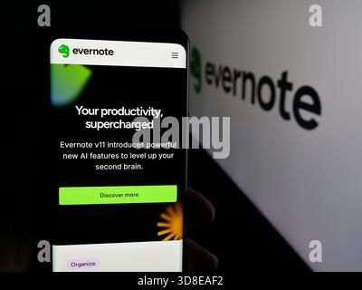 Stoccarda, Germania - 11-19-2025: Persona che detiene il cellulare con pagina web della società di software per appunti Evernote sullo schermo davanti al logo. Foto Stock