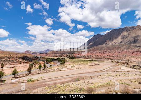 Arido paesaggio di potosi, bolivia, con montagne, letti di fiume asciutti e una piccola comunità Foto Stock