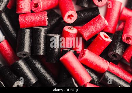 Primo piano di pezzi di caramelle rosse e nere alla liquirizia sparsi in modo casuale Foto Stock