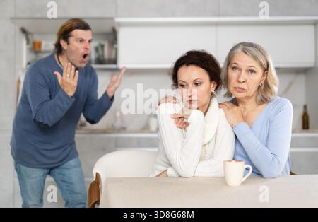 La vecchia conforta sua figlia mentre suo marito le urla contro Foto Stock