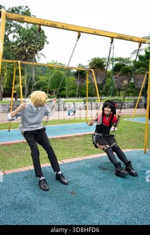 Due cosplayer si divertono a giocare su un'altalena all'interno di un parco giochi Foto Stock
