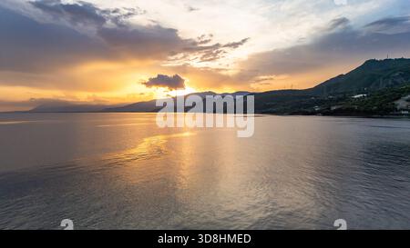 Vista aerea con droni di un vibrante tramonto sul Golfo di Corinto nella Grecia centrale, catturato dal villaggio di Skaloma. Cieli colorati, mare calmo. Foto Stock