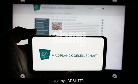 In questa illustrazione fotografica, una persona ha in mano un cellulare con il logo dell'organizzazione di ricerca Fraunhofer-Gesellschaft sullo schermo davanti alla pagina web. Foto Stock