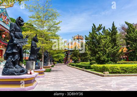 Statue di guerrieri neri lungo la passerella del giardino sotto il cielo blu al santuario cinese Suphan Buri Foto Stock