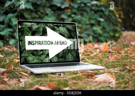 Notebook che mostra un messaggio motivazionale di ispirazione davanti a te e una freccia che punta in avanti, in un ambiente naturale all'aperto con il baluardo autunnale caduto Foto Stock