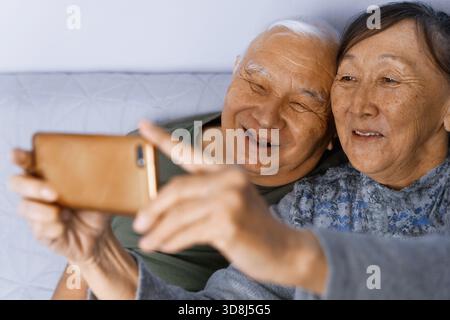 Una coppia anziana a casa a fare un selfie Foto Stock