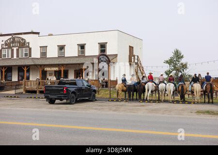 I Cowboys siedono sui cavalli fuori dal salone nella città occidentale canadese Foto Stock