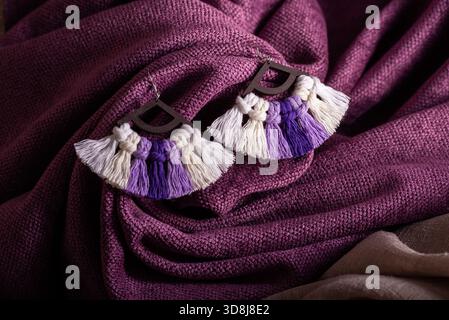 Un primo piano di orecchini con nappina in macrame realizzati a mano con un design a ventaglio. Foto Stock