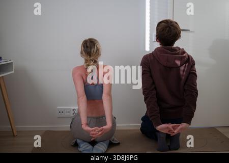 coppia che si allunga sui tappetini da yoga a casa durante l'allenamento mattutino Foto Stock