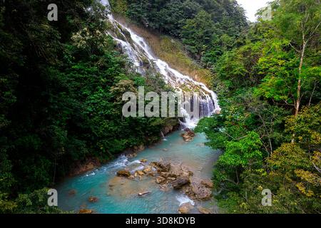 La magica cascata di Lapopu che si riversa su rocce a più livelli in una piscina turchese circondata da una lussureggiante foresta pluviale a Sumba, Indonesia. Foto Stock