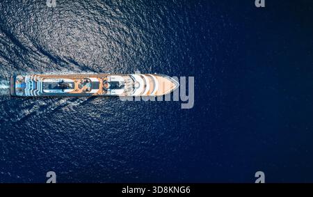Vista aerea dall'alto di una nave da crociera di lusso o di uno yacht di lusso che naviga sullo scintillante oceano blu come concetto di viaggio con spazio fotocopie< Foto Stock