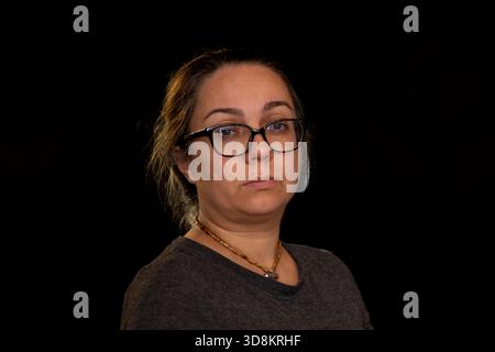 Ritratto in studio di una donna con occhiali su sfondo scuro Foto Stock