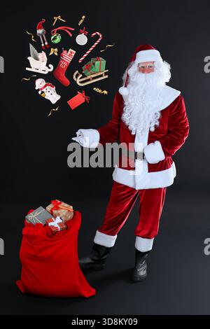Babbo Natale, decori natalizi e scatole regalo su sfondo nero. Magia festiva Foto Stock