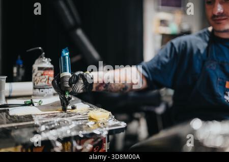 Tatuatore al lavoro con macchina per tatuaggi che crea audaci body art in studio Foto Stock