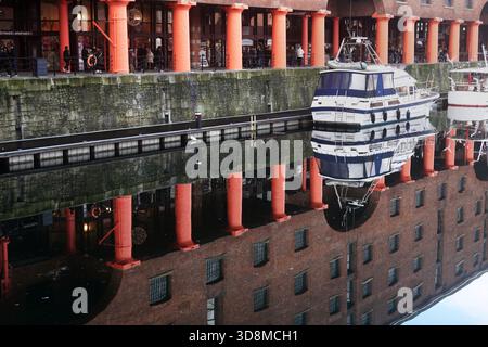 I riflessi delle colonne rosse di Albert Dock, dei magazzini di mattoni e delle barche ormeggiate si rispecchiavano perfettamente sulle acque calme di Liverpool. Foto Stock