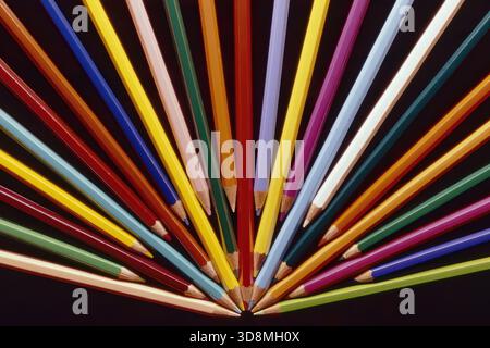 Pastelli lucidi di vari colori disposti a ventaglio su sfondo nero Foto Stock