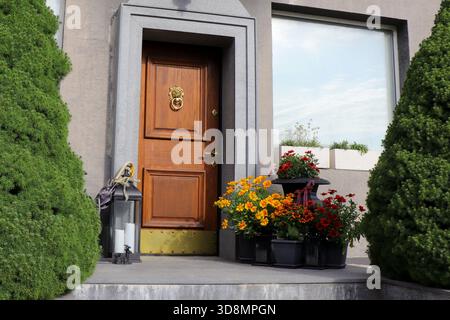 Giallo brillante Gaillardia e fiori di Rudbeckia arancio-rosso disposti in vasi decorativi da un ingresso di casa in legno. Piante colorate che creano un Foto Stock