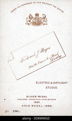 Pubblicità studio per Frederick J. Boyes della 22 & 24 Osmaston Road, Derby. Con stemma reale, medaglie e motivi a busta. Mette in risalto lo studio elettrico e diurno, con il patrocinio della Regina Vittoria e il riferimento della stampa numerata. Da un album fotografico del tardo vittoriano a quello del primo edoardiano, che presentava molte carte di albume e carte de visites, fornendo una finestra sugli stili e le mode dell'epoca. Foto Stock