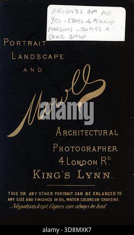 Un'impronta decorata in studio per Mowll, fotografo di architettura, presenta tipografia stilizzata e decorazioni floreali. L'indirizzo stampato è 4 London Road, King's Lynn, con servizi di fotografia ritrattistica, paesaggistica e architettonica. Vengono offerti ingrandimenti in olio, acquerello o pastello; i negativi vengono mantenuti. Da un album fotografico del tardo vittoriano a quello del primo edoardiano, che presentava molte carte di albume e carte de visites, fornendo una finestra sugli stili e le mode dell'epoca. Foto Stock
