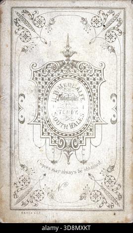 Un'impronta decorata in studio per H. B. Medcalfe di Tenby, Galles del Sud, incorniciata da motivi simmetrici a scorrimento e motivi floreali. La scritta incisa si trova all'interno di un cartiglio decorativo. "Una nota riportata di seguito recita "è sempre possibile ottenere copie"." "Il supporto include "Back & Co." in piccolo formato." Da un album fotografico del tardo vittoriano a quello del primo edoardiano, che presentava molte carte di albume e carte de visites, fornendo una finestra sugli stili e le mode dell'epoca. Foto Stock