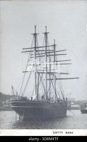 Una fotografia in bianco e nero della nave clipper Cutty Sark attraccata nel porto. I suoi alti alberi e le sue attrezzature dominano la cornice, con edifici costieri e alberi sullo sfondo. L'immagine cattura le eleganti linee dell'imbarcazione e la sua presenza duratura nella storia marittima. Da un album fotografico del tardo vittoriano a quello del primo edoardiano, che presentava molte carte di albume e carte de visites, fornendo una finestra sugli stili e le mode dell'epoca. Foto Stock