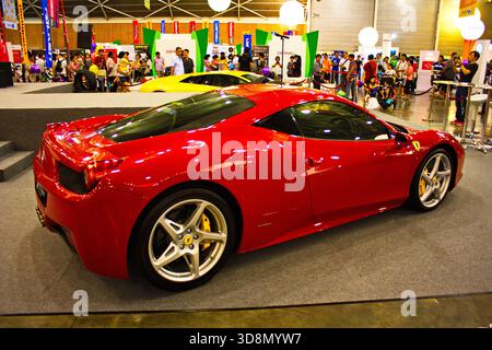 Le curve lucide e cremisi Ferrari 458 Italia dominano la sala espositiva con pavimento grigio lucido e sfondo tecnico Foto Stock