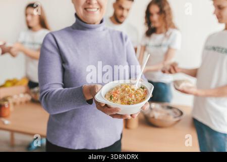 Gruppo di amici che si divertono a cucinare in un luminoso spazio cucina Foto Stock