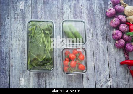 Verdure fresche conservate in contenitori di vetro su un tavolo di legno Foto Stock