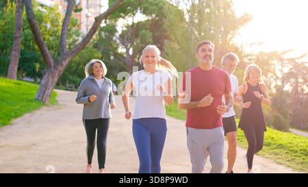 Amici maturi che corrono insieme in un parco Foto Stock