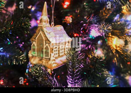 Giocattolo per la casa del ghiaccio su un albero di Natale con luci colorate Foto Stock