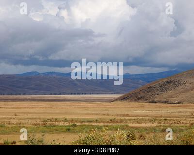 Vallata e arida e paesaggio collinare sotto pesanti e drammatiche nuvole di tempesta Foto Stock
