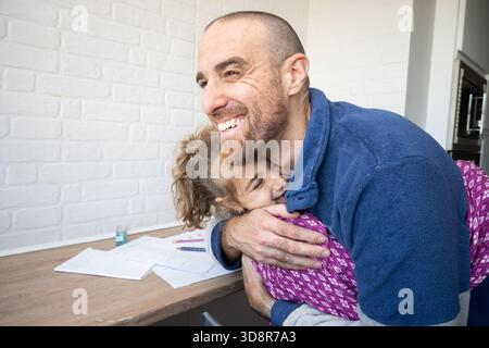 Padre abbraccia sua figlia dopo aver finito i compiti a scuola Foto Stock