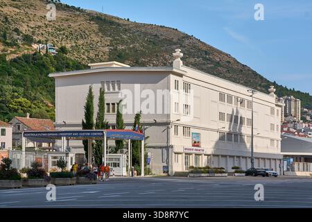 Dubrovnik. Croazia - 2 dicembre 2025: Turisti che camminano di fronte all'ingresso del controllo doganale del porto di Gruz con la grande collina e la città di Hou Foto Stock