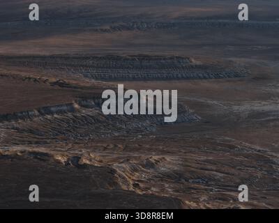 Arido altopiano del deserto che presenta vaste formazioni geologiche e intricati schemi di erosione, rivelando strati di roccia e. Foto Stock