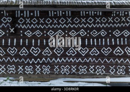 Motivi geometrici bianchi adornano la facciata di una casa in legno scuro a Cicmany, Slovacchia Foto Stock