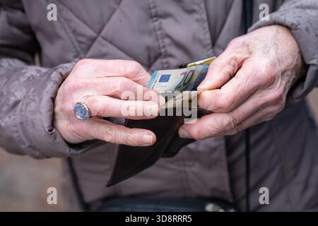 2 dicembre 2025, Brema: Le mani di una persona anziana hanno un portafoglio aperto con una banconota da 20 euro. Venerdì, il Bundestag deciderà la riforma pensionistica prevista, che prevede un livello pensionistico stabile, periodi prolungati di crescita dei figli, possibilità di reddito supplementare esentasse in età avanzata e altre modifiche alle pensioni di vecchiaia. Foto: Sina Schuldt/dpa Foto Stock