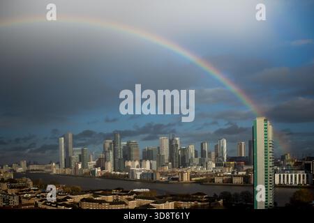 Londra, Regno Unito. 2 dicembre 2025. Meteo nel Regno Unito: Un enorme arcobaleno si rompe nella zona est di Londra con gli edifici del parco commerciale Canary Wharf in vista dopo un breve temporale pomeridiano. Crediti: Guy Corbishley/Alamy Live News Foto Stock