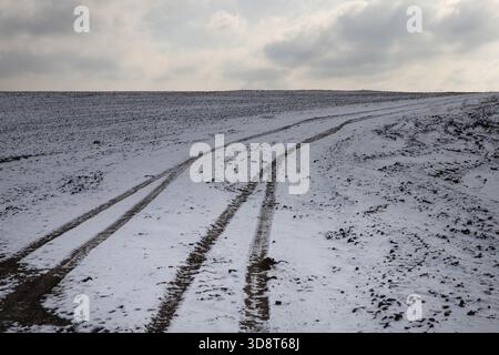 Cingoli per pneumatici invernali su strade innevate che attraversano un paesaggio freddo e arido Foto Stock