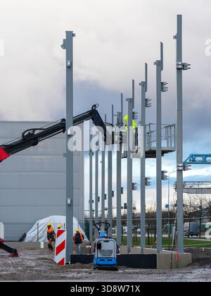 Lavoratori che installano colonne di supporto in acciaio con movimentatore telescopico in cantiere industriale Foto Stock