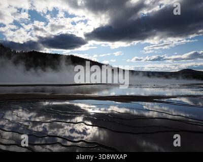 Vista suggestiva del vapore che si innalza da una piscina termale nel Midway Geyser Basin, stagliato contro un cielo nuvoloso con la luce del sole che si irrompe. Foto Stock