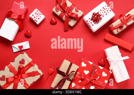 Cornice realizzata con bellissime confezioni regalo e caramelle su sfondo rosso. Festa di San Valentino Foto Stock