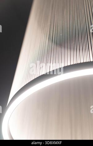 In a luxurious setting, a beautifully designed light fixture casts a warm glow, creating abstract patterns on nearby surfaces. The ambiance exudes sophistication and elegance. Foto Stock