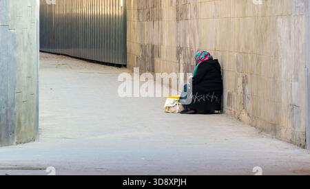 Erevan Armenia 10.25.2025. Una donna anziana è seduta e vende candele per la chiesa. Indossa una sciarpa e un cappotto nero Foto Stock