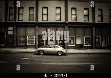 Porsche 365 d'epoca d'argento parcheggiata di fronte a un vecchio edificio in tonalità seppia Foto Stock
